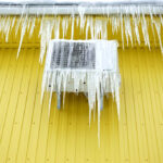 Frozen,Air,Conditioner,In,Ice,Icicles,On,A,Yellow,Wall.